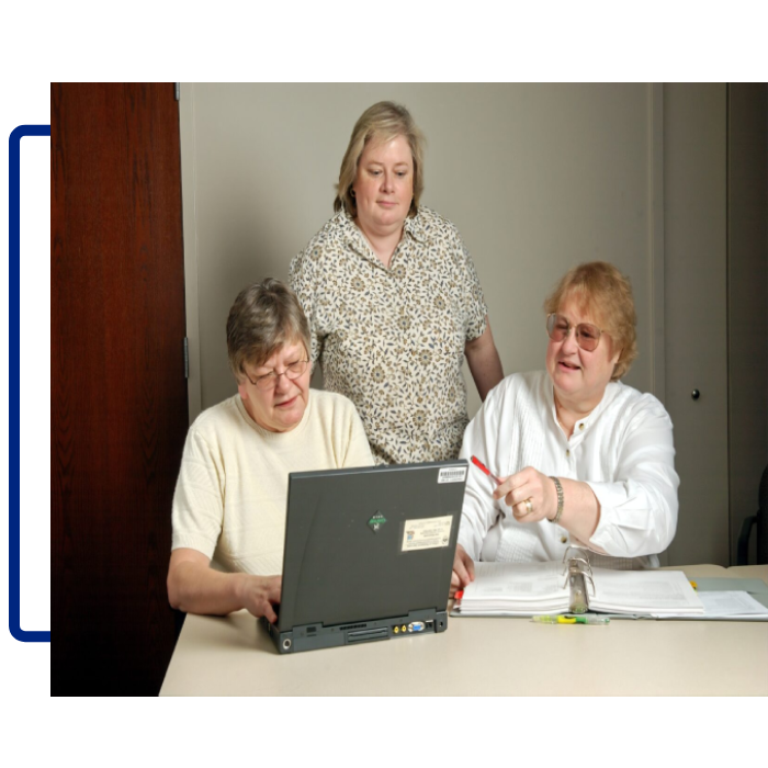 Three women sitting at a table with a laptop.